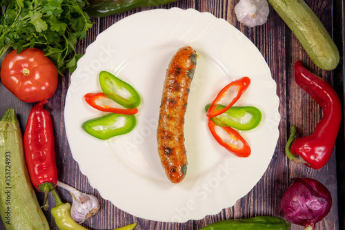 Gourmet beef sausage served with sliced pepper, on a white plate on a plate, Top view
