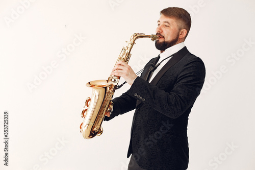 Man in a studio. Guy in a black suit. Musician with saxophone.