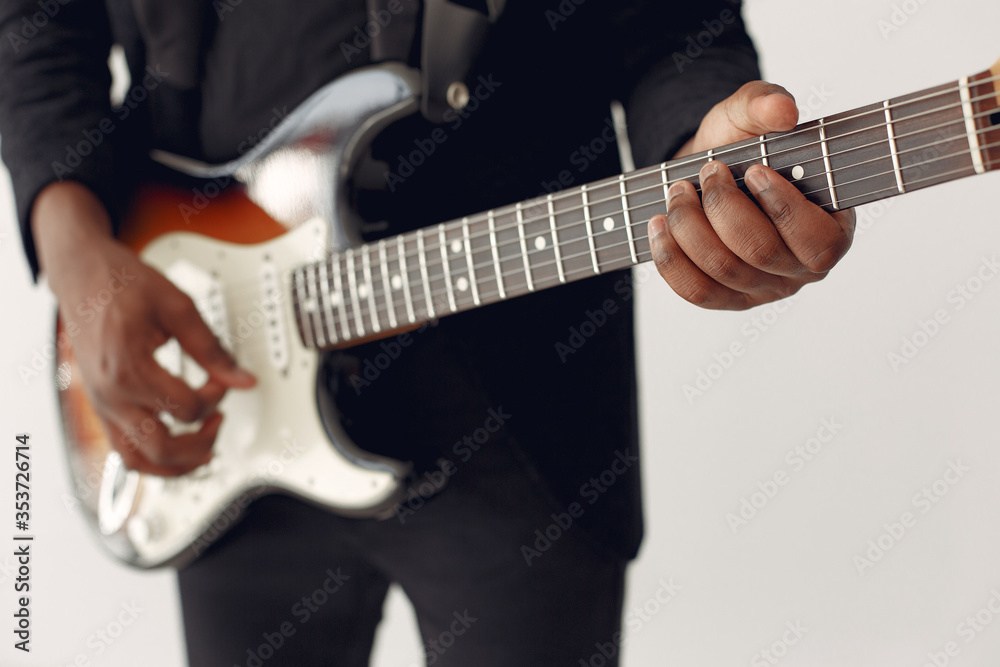 Black man in a studio. Guy in a black suit. Musician with a guitar.