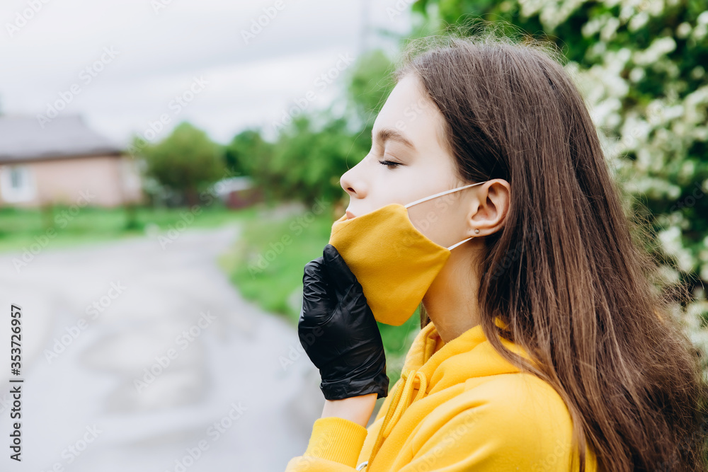Plakat Girl wearing stylish handmade protective face mask posing on street. Fashion during quarantine of coronavirus outbreak.