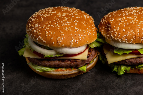 2 burgers on dark gray wooden background, сopy space on left side 