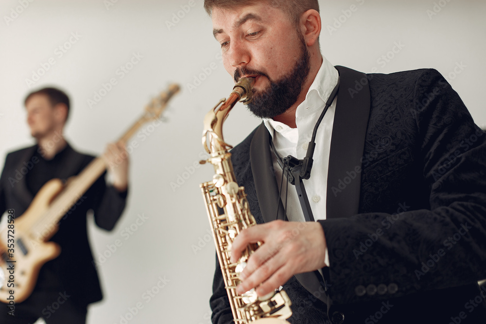 Fototapeta premium Music band in a studio. Guy in a black suit. Musician with saxophone.
