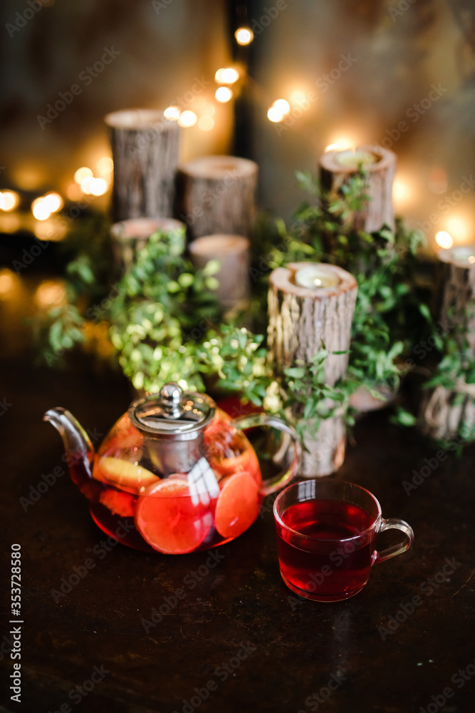 Naklejka premium Red author's tea in a transparent teapot on the table against the background of greenery