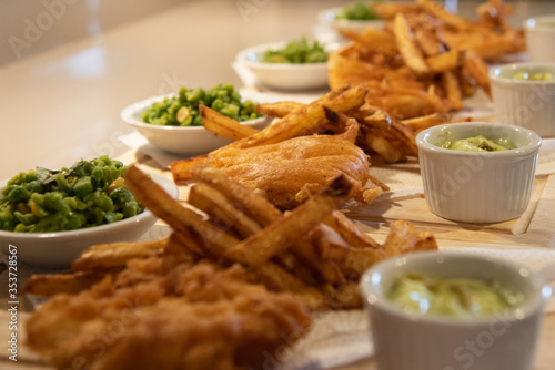 Fish & chip meal with peas on wooden plating board. Tasty meal dinner seafood.
