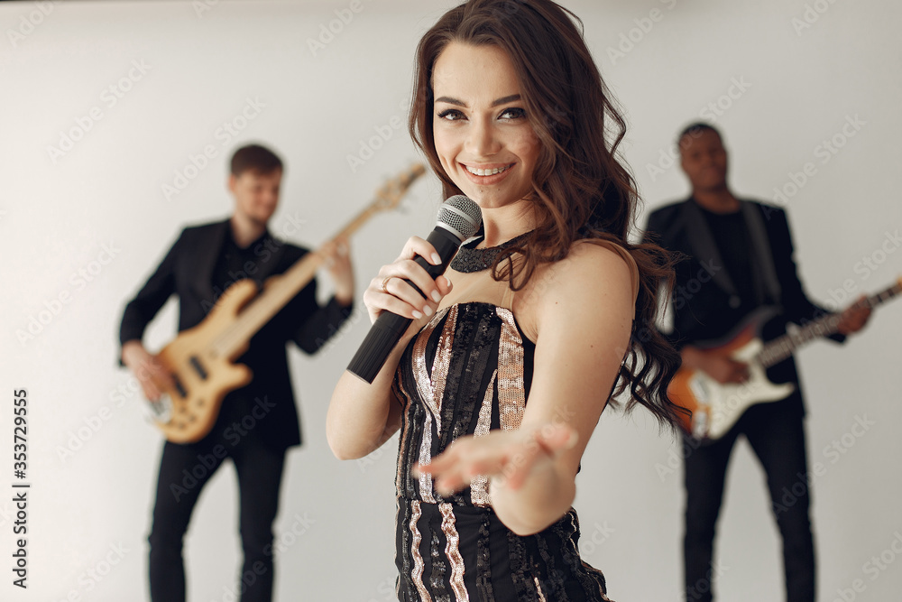 Music band in a studio. Guy in a black suit. Musician with saxophone. Woman with a microphone.