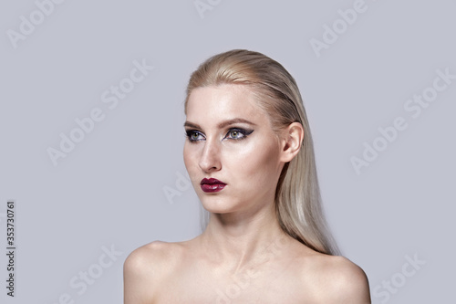 Bright make-up in a woman with bare shoulders. Stylish haircut.