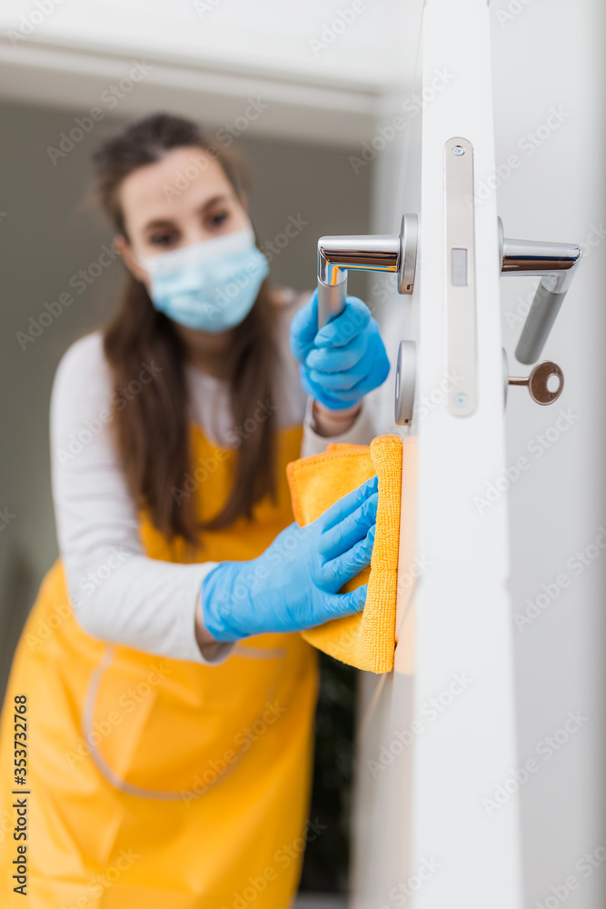 Woman housekeeper wipes the door with rag. Housekeeping concept. - obrazy, fototapety, plakaty 