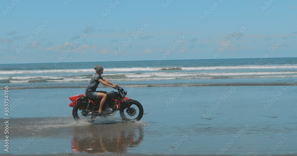 Obraz premium Motorcyclist driving his motorbike on the beach