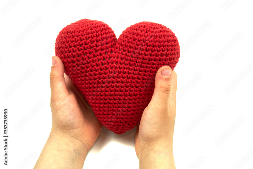 Red heart in child hands isolated on white background. Red plush heart in child hands on white.