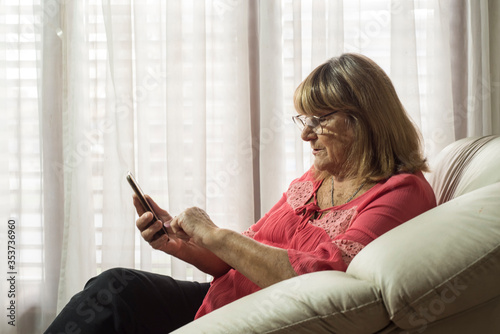 older woman using modern technologies on her devices to communicate while meeting social distancing
