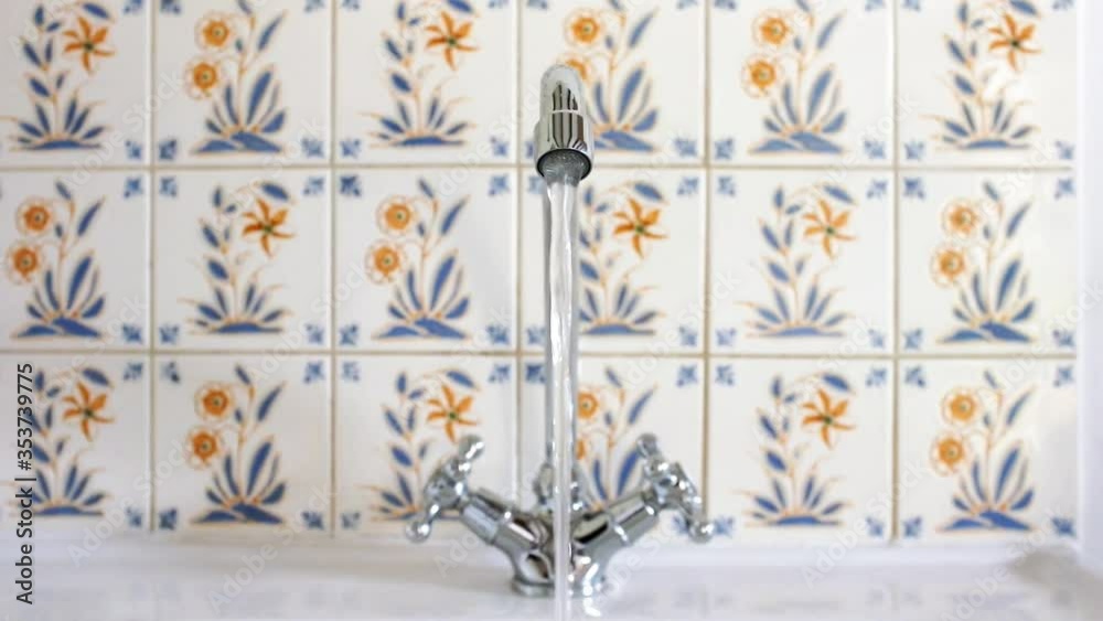 Water flowing from a running faucet into sink Water flowing from a running faucet into sink