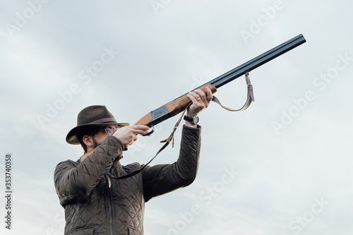Vintage hunter walks. Rifle Hunter Silhouetted in Beautiful Sunset or Sunrise. Hunter aiming rifle in swamp and field