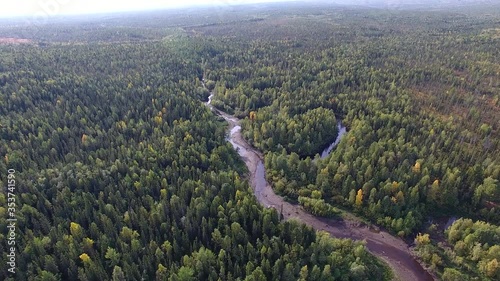 Small River in Coniferous Forest.	Top view of the coniferous forest in autumn. A small river flows past the forest. Taiga in the North of Siberia