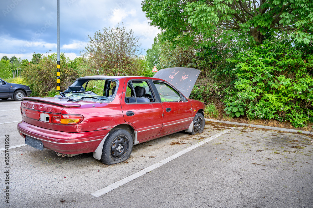 Destroyed abandoned car with broken car glasses, flat tires and open hood