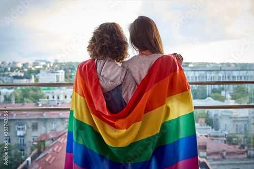 Two girls looking out the window at the city with rainbow flag photo