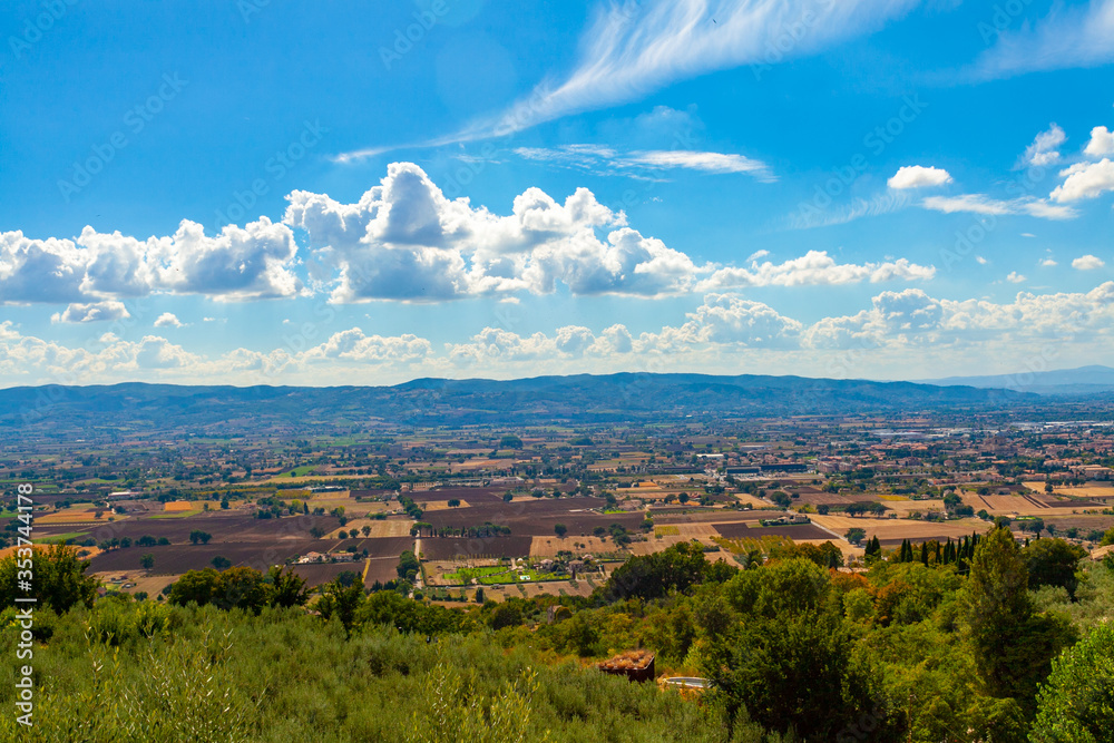 Veduta del paesaggio della piana di Spoleto da Assisi, Umbria, Italia, in una giornata di sole con cielo blu e nuvole bianche