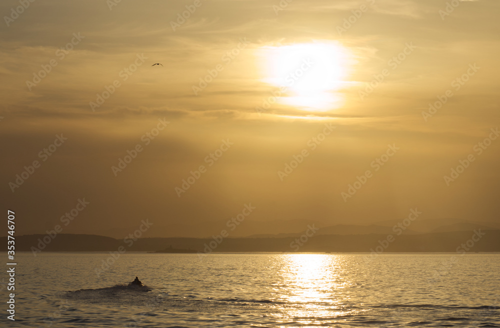 Motor boat setting into the sunset on the Firth of Forth in Edinburgh