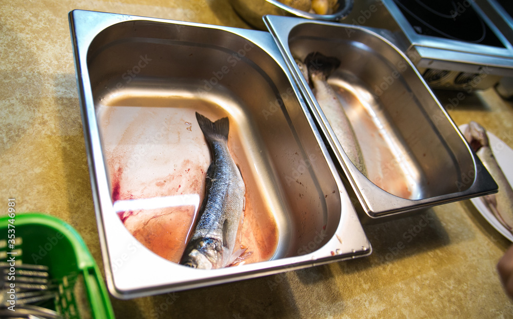 raw sea bass fish in a metal bowl raw sea bass fish in a metal bowl