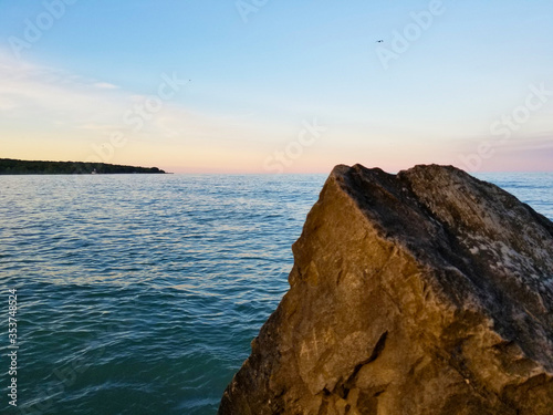 View of a rock by lake during a summer sunset