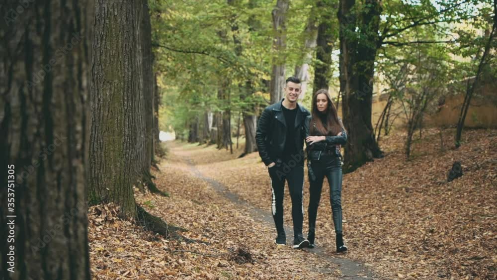 A loving couple walks in autumn park. Blurred beginning. Strong guy is hugging is girlfriend. Slow motion. Copy space. 4K. A loving couple walks in autumn park. Blurred beginning. Strong guy is hugging is girlfriend. Slow motion. Copy space. 4K.