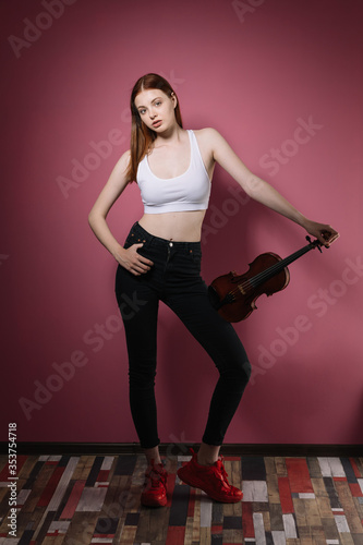 Girl in black plays violin on pink background