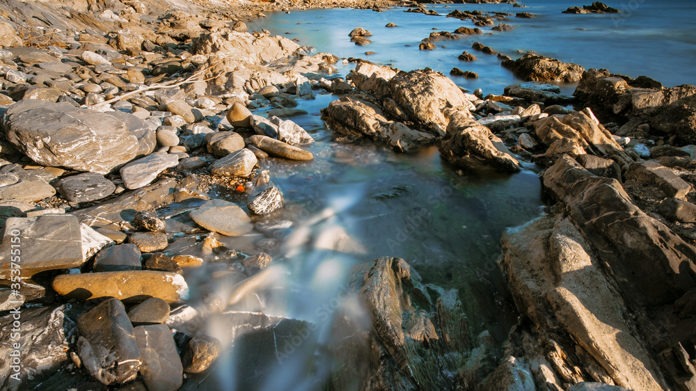 Rocky coast bay of Tyrrhenian sea. Water on long exposure. Sunlight effect. Tourism and vacation, travelling concept. Geographic features banner.