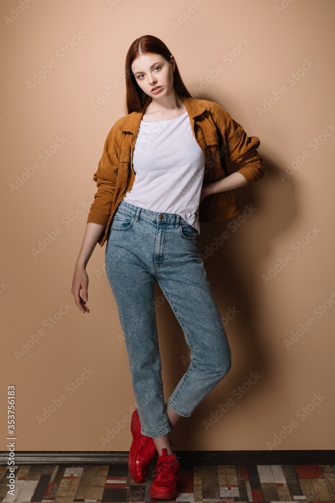 Girl in jeans and a brown jacket posing on a beige background Stock ...