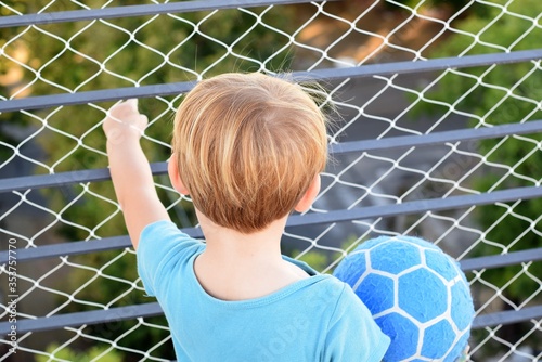 Two years old blond boy playing at the terrace during quarantine for coronavirus. There is a security net on the balcony. 21st March, 2020, Buenos Aires, Argentina.