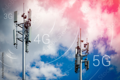 Two telecommunication towers with 4G, 5G transmitters. Cellular base stations with transmitting antennas on a telecommunication tower on a background of blue sky with pink-yellow clouds. photo