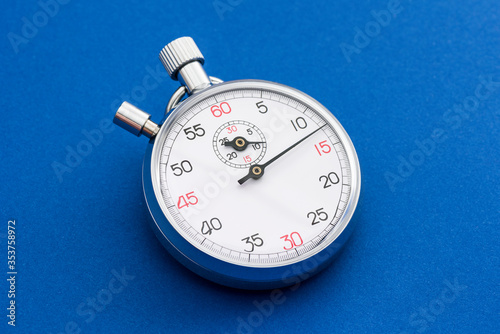 Analogue metal stopwatch on the blue background.