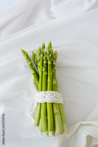 A bunch of green asparagus on a light background. Asparagus tied with lace ribbon.