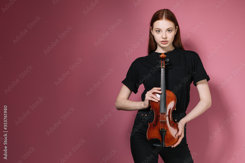 Girl in black plays violin on pink background