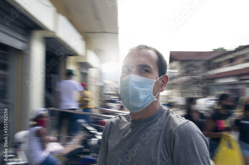 a young dominican man wearing protective mask in street surrounded by people back to normal life