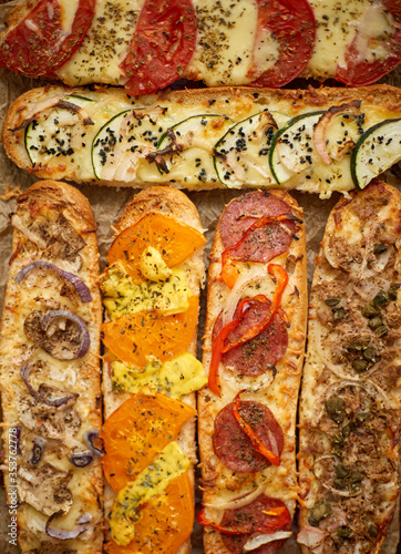 Assortment of various toppings baked sandwiches. With melted cheese, vegetables, tuna, olives spices