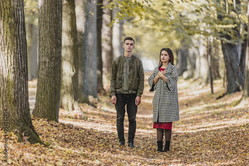 Full-length shot of boy and girl in autumn park, looking anxious, living through some problems and misunderrstanding. © Andrii