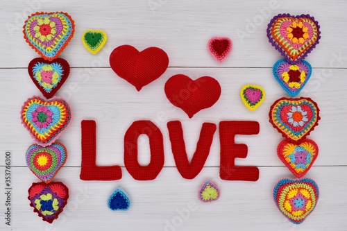 Knitted hearts and the word love are placed on white wooden boards.