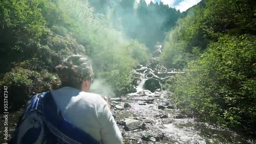 Slow reveal of a beautiful woman shaman sangoma offering burning plant medicine to honor her ancestors near a mountain stream photo