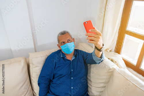 older man having a video call on his cell phone while at home on covid19