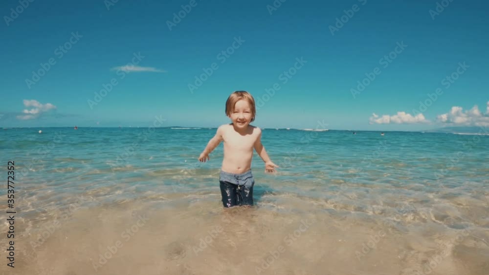 Young caucasian boy splashes water in beautiful clear waters at beach. Location Hawaii. Young caucasian boy splashes water in beautiful clear waters at beach. Location Hawaii.