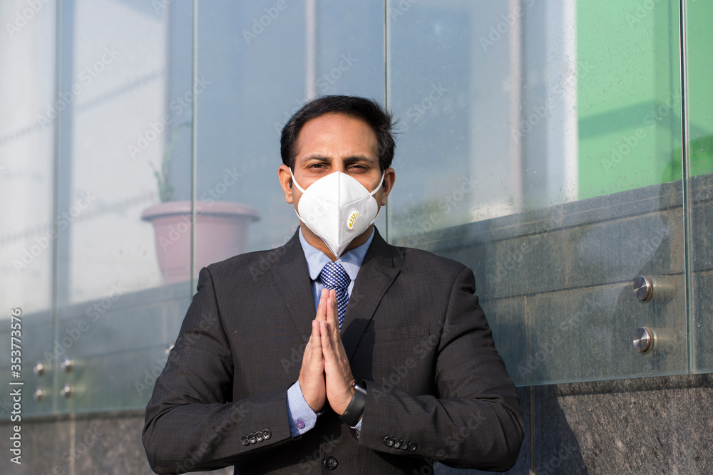Businessman wearing face mask and greeting with namaste to prevent spread of virus. Businessman wearing face mask and greeting with namaste to prevent spread of virus.
