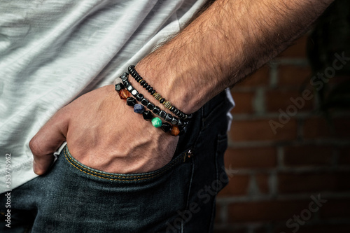 Fotografia Fashion bracelets made of natural stones and minerals, close-up, hand in pocket