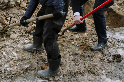 Billede på lærred A businessman and a worker dig a hole, shovels the soil to cover the grave and bury the dead