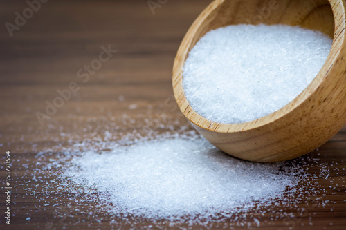 Monosodium glutamate ( MSG ) in wooden bowl pouring on rustic wooden table background. Selective focus.