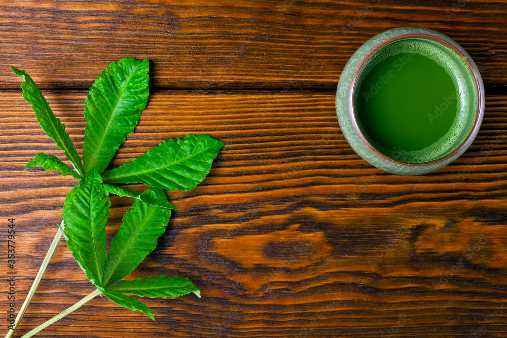 Matcha tea in a cup and green leaves on a wooden background. Top view. Matcha tea in a cup and green leaves on a wooden background. Top view.
