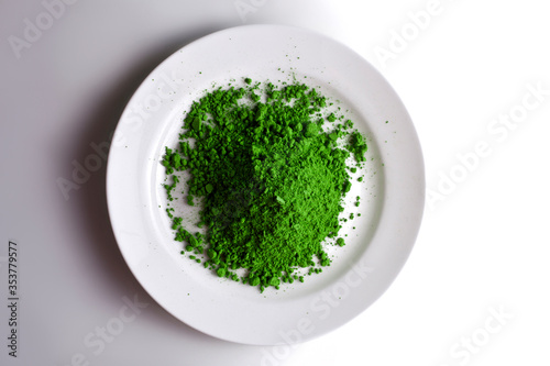 Heap of powdered matcha tea in a plate on a white background. Top view.