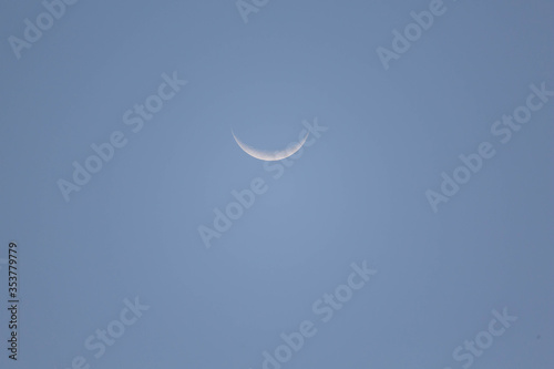 Moon first quarter in day time with clear blue sky with visible crater lands scape, shot with 600mm zoom lense photo