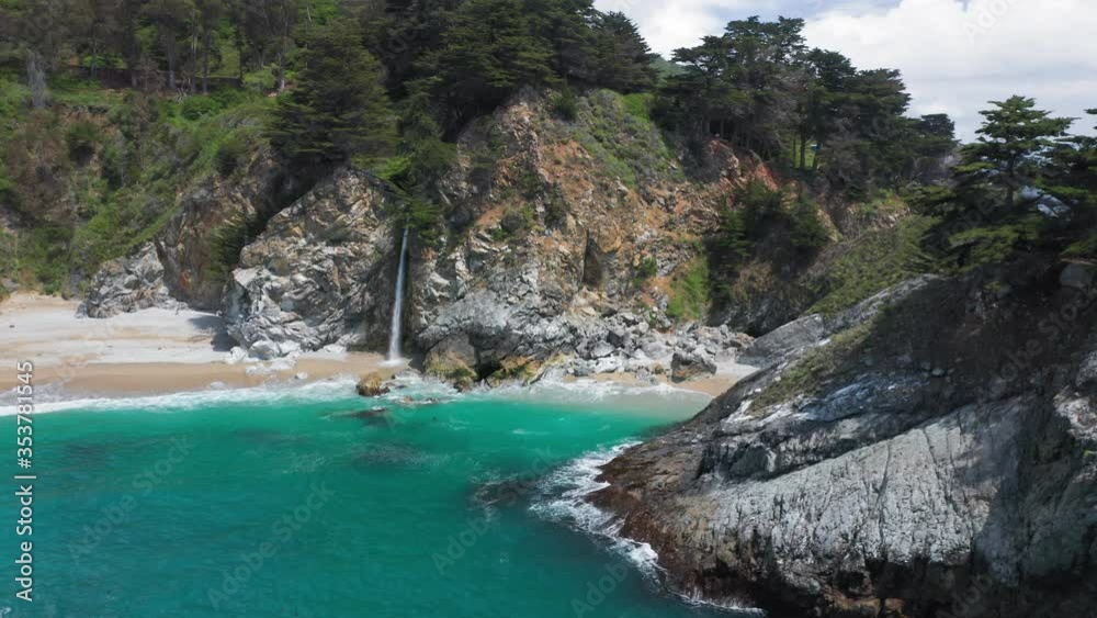 Stunning aerial view of the wild nature. The slim waterfall crashes from the high cliff into the deep green-blues Pacific Ocean waters. World-famous Big Sur coastline tourism landmark. 4K, USA Stunning aerial view of the wild nature. The slim waterfall crashes from the high cliff into the deep green-blues Pacific Ocean waters. World-famous Big Sur coastline tourism landmark. 4K, USA