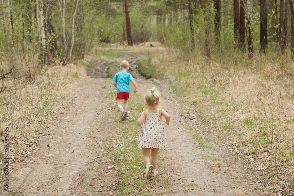 Obraz premium Brother and sister walk along the forest road