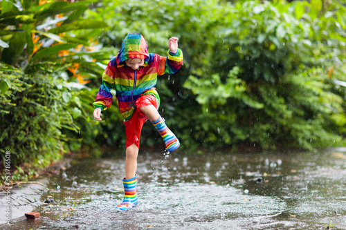 Fototapeta Naklejka Na Ścianę i Meble -  Kids in puddle in autumn rain. Waterproof wear