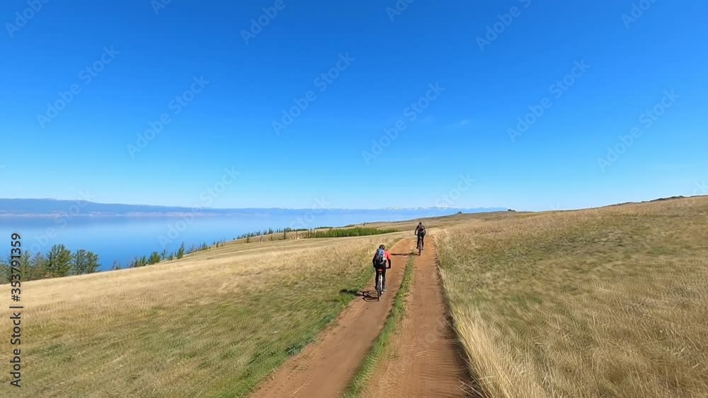 Young sports man and girl riding bicycles at the rural road over field. Sporty guy girl cycling along country trail outdoor. Healthy active lifestyle Slow motion Young sports man and girl riding bicycles at the rural road over field. Sporty guy girl cycling along country trail outdoor. Healthy active lifestyle Slow motion